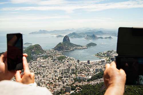 cell phone two person holding tablet computer and smartphone in elevated place with the view of city during daytime mobile phone